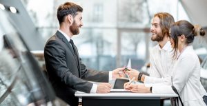 A sales rep talks to a couple about their want to buy a new vehicle.